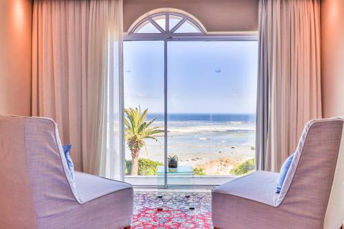 a room with a large window with a view of the ocean at Hermanus Beachfront Lodge - Solar Power in Hermanus