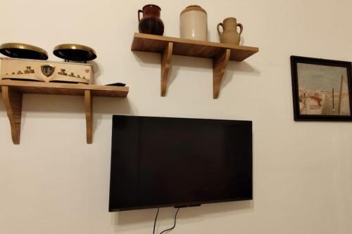 a flat screen tv sitting on a wall with shelves at A casa di Gino in Molfetta