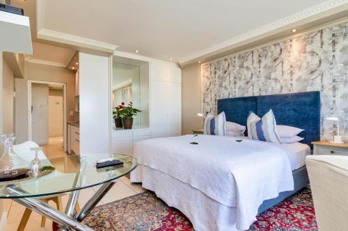 a bedroom with a large bed and a glass table at Hermanus Beachfront Lodge - Solar Power in Hermanus