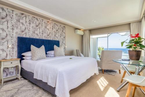a bedroom with a large bed and a table at Hermanus Beachfront Lodge - Solar Power in Hermanus
