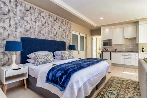 a bedroom with a large bed and a kitchen at Hermanus Beachfront Lodge - Solar Power in Hermanus