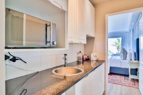 a kitchen with a sink and a bed at Hermanus Beachfront Lodge - Solar Power in Hermanus
