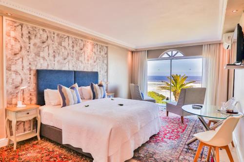 a bedroom with a large bed and a view of the ocean at Hermanus Beachfront Lodge - Solar Power in Hermanus