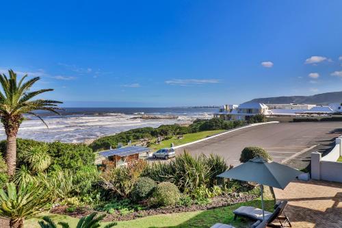 a view of the ocean from a house with an umbrella at Hermanus Beachfront Lodge - Solar Power in Hermanus