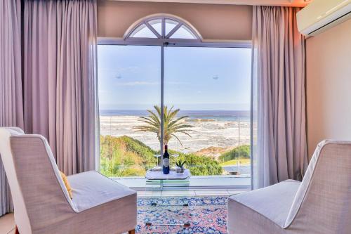 a room with a large window with a view of the ocean at Hermanus Beachfront Lodge - Solar Power in Hermanus