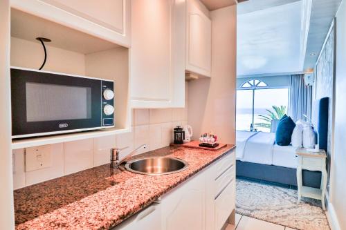 a kitchen with a sink and a microwave at Hermanus Beachfront Lodge - Solar Power in Hermanus