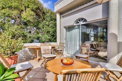 a patio with a wooden table and chairs on a patio at Hermanus Beachfront Lodge - Solar Power in Hermanus