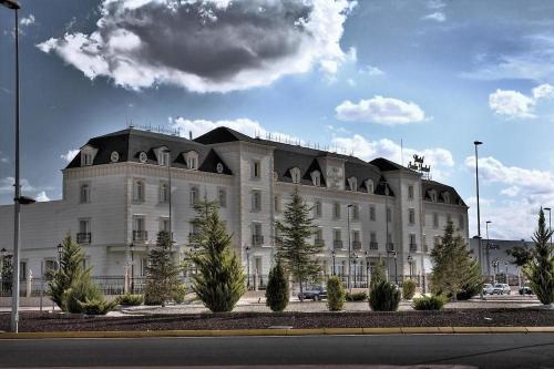a large white building with trees in front of it at Hotel Bossh Alicia in Albacete