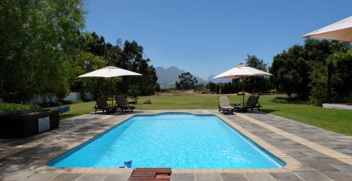 a swimming pool with two chairs and umbrellas at Vine Guesthouse in Stellenbosch