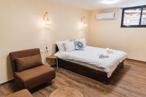 a small bedroom with a bed and a chair at שיח מדבר לינה בנגב Burning Bush Negev in Merhav Am