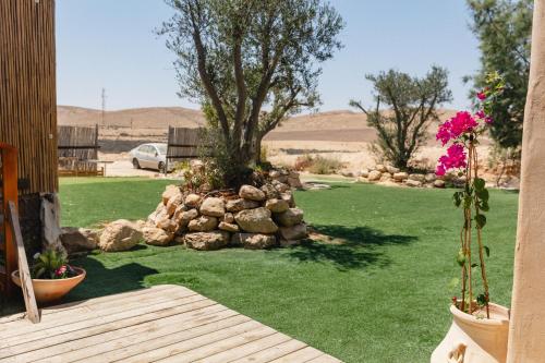 a yard with green grass and a rock wall at שיח מדבר לינה בנגב Burning Bush Negev in Merhav Am