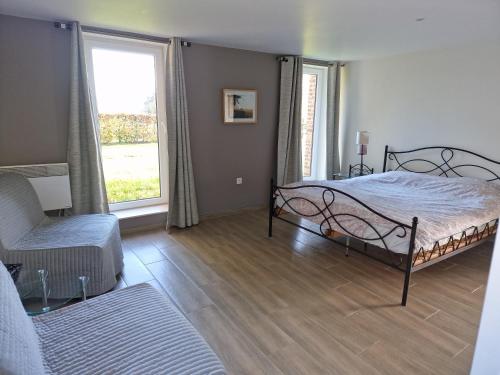 a bedroom with a bed and a chair and windows at Gite des étangs à Montzen in Plombières
