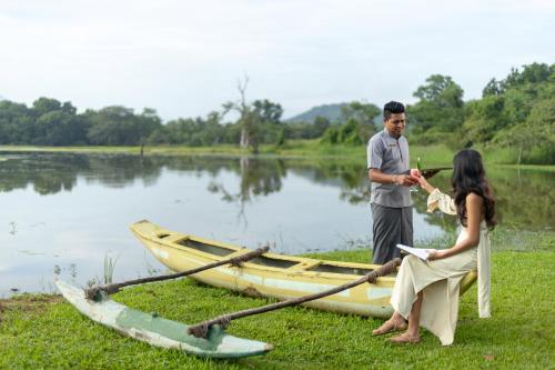 a man and a woman standing next to a boat at Jetwing Lake in Dambulla