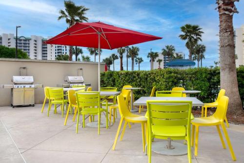 a group of tables and chairs with a red umbrella at Home2 Suites by Hilton Destin in Destin