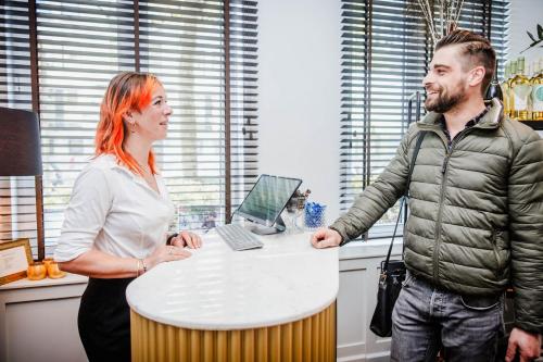 a man and woman standing next to a table with a laptop at Boutique hotel Maison Emile in Antwerp