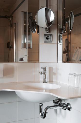 a bathroom with a white sink and a mirror at Home Hotel Grand Sundsvall in Sundsvall