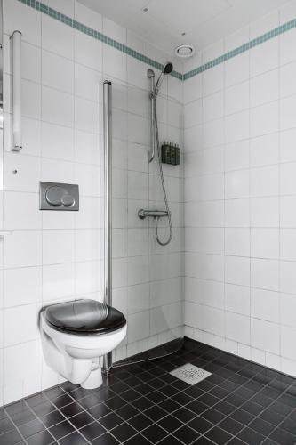 a bathroom with a toilet with a black seat at Home Hotel Grand Sundsvall in Sundsvall