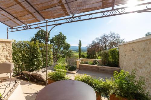 an outdoor patio with a table and chairs and a pergola at Coquillade Provence - Relais & Châteaux in Gargas