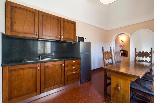 a kitchen with wooden cabinets and a stainless steel refrigerator at Certosa di Pontignano Residenza d'Epoca - Place of Charme in Ponte A Bozzone