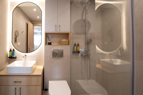 baño con 2 lavabos, ducha y 2 espejos en Eria Suites Thessaloniki, en Tesalónica