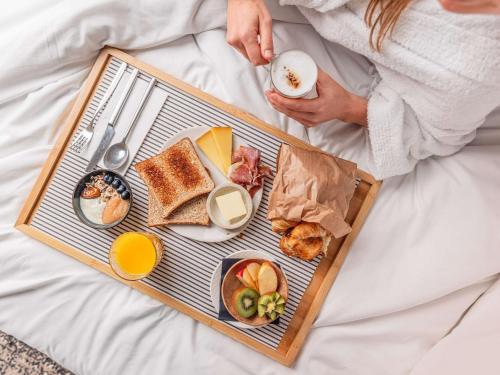 a tray of breakfast foods on a bed at Novotel Nairobi Westlands in Nairobi