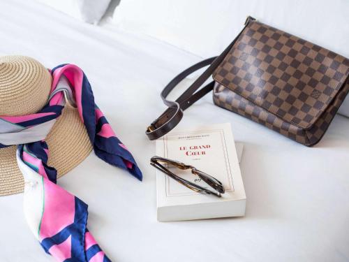 a pen and a book on a bed with a purse at Novotel Nairobi Westlands in Nairobi