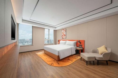 a bedroom with a white bed and a chair at Hilton Garden Inn Tianjin Railway Station in Tianjin