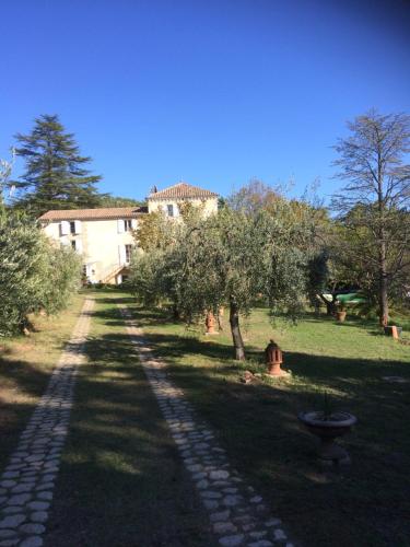 une route pavée en face d'une maison arborée dans l'établissement La Bastide de Villecroze, à Villecroze