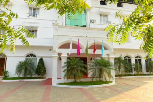 a white building with palm trees in front of it at Paray Village County in Kollengode