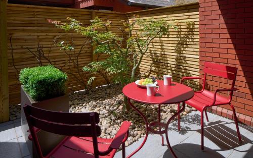 a red table and chairs on a patio at Cheval Knightsbridge in London