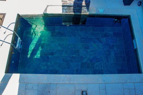 a blue swimming pool with a person in the water at Villa Kaskavel in Les Avirons