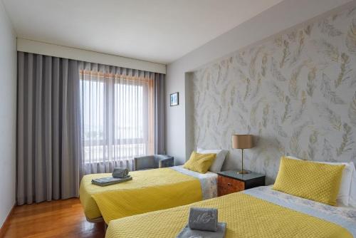 a hotel room with two beds and a window at Avenida: Central, Garage, Metro in Vila Nova de Gaia