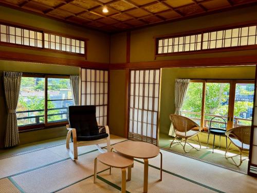 a room with chairs and a table and windows at Kusatsu Onsen Kusatsu Hotel1913 in Kusatsu
