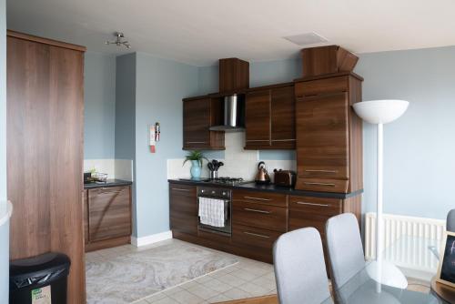 a kitchen with wooden cabinets and a glass table at City Hall Penthouse Duplex - Incredible Views & Sleeps 8 & Balcony & Very Modern and spacious in Belfast