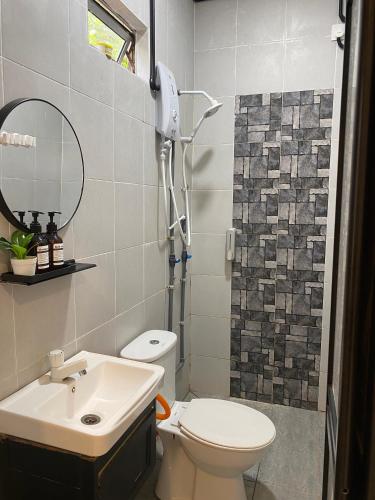 a bathroom with a toilet and a sink and a mirror at Rajawali Riverside Retreat in Dungun