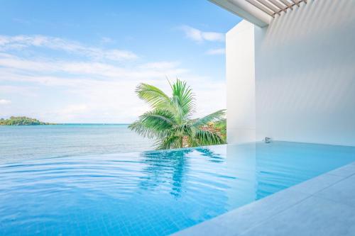 a swimming pool with a palm tree and the ocean at Villa VALIOSA ON THE BEACH in Onna