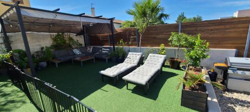 a backyard with a lawn with chairs and an umbrella at Magnifique villa à 15mn des plages in Fabrègues