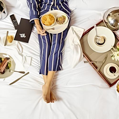 a woman laying on a bed with a plate of food at Hôtel L'ile Du Saussay in Itteville