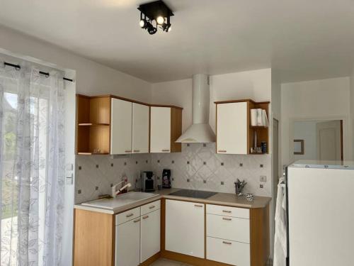 une cuisine avec des armoires blanches et un réfrigérateur blanc dans l'établissement Maison ville confort, au Faouët