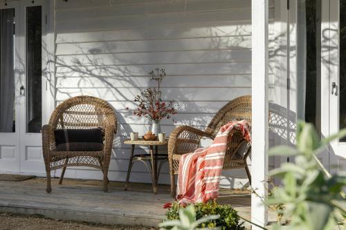 una veranda con 2 sedie in vimini e un tavolo di Little Oak - Place to Relax and Create Memories a Cygnet