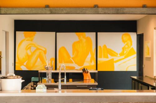 a kitchen with four pictures on the wall at La Villa Flore - 5 chambres, piscine et jacuzzi in La Saline les Bains