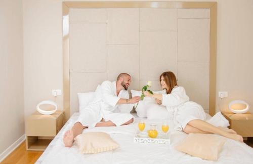 a man and a woman sitting on a bed at TC BiG APARTMENTS in Budva
