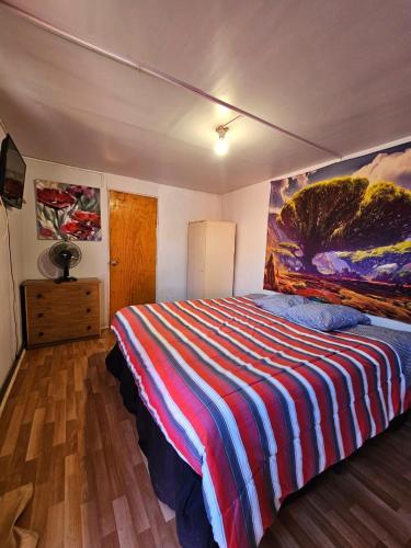a bedroom with a bed with a painting on the wall at El valle in Copiapó
