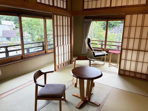 a room with chairs and a table and windows at Kusatsu Onsen Kusatsu Hotel1913 in Kusatsu