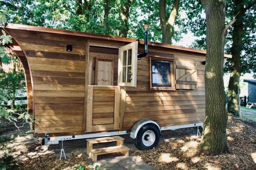 a wooden tiny house parked next to a tree at Charmantes Tiny House am Rande der Lüneburger Heide in Kirchlinteln