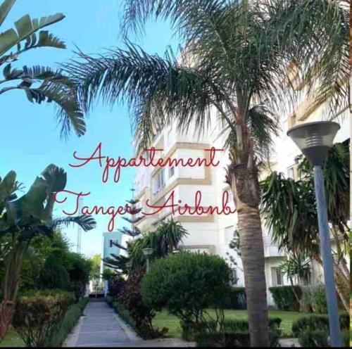 a sign for a resort with palm trees and a building at Moderne appartement met tuin in Tangier