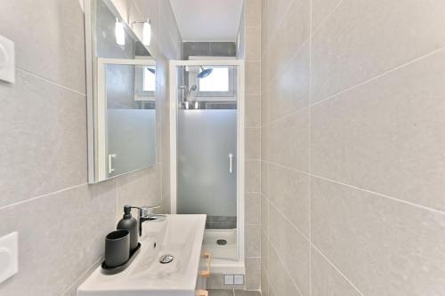 une salle de bain blanche avec un lavabo et un miroir dans l'établissement Magnifique 2 pièces dans la banlieue parisienne, à Montreuil
