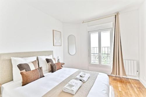 - une chambre blanche avec un grand lit et des serviettes dans l'établissement Magnifique 2 pièces dans la banlieue parisienne, à Montreuil