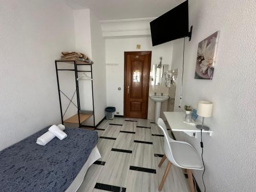 a bedroom with a bed and a desk and a table at Hostal Arrate in Madrid