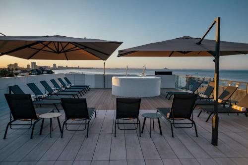 a deck with chairs and tables and umbrellas at Hotel Cetina Cabo de Palos Puerto in Cabo de Palos